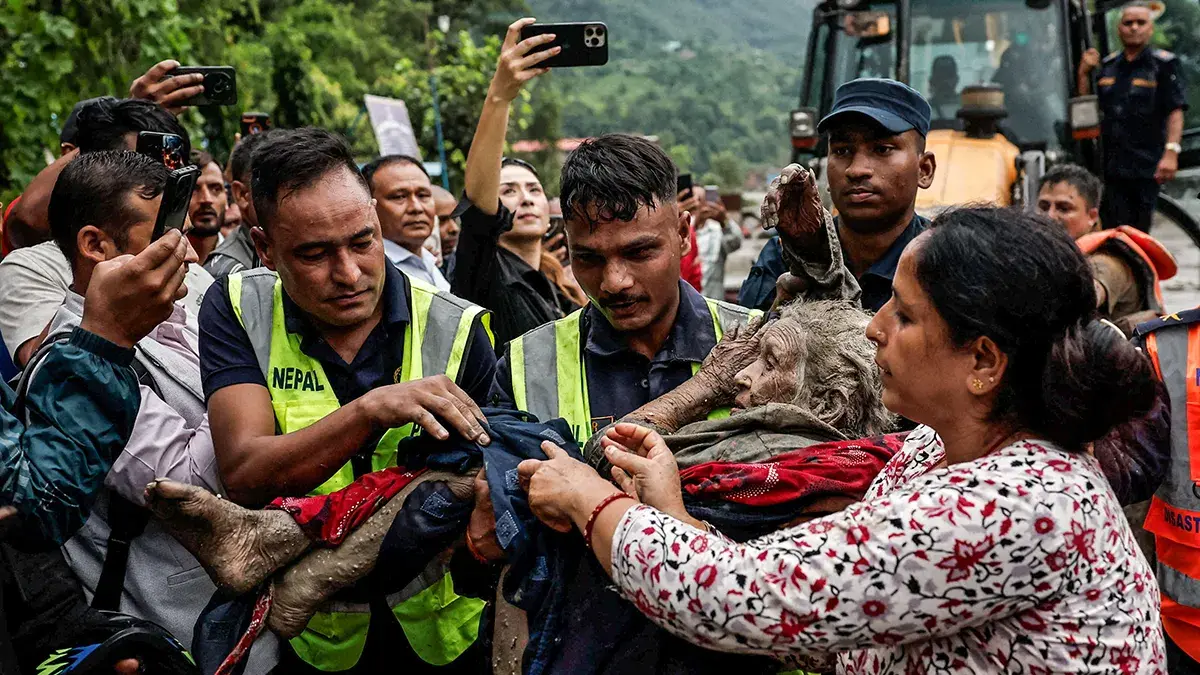 Residents helping an elderly neighbor to safety through a flood-hit area in northern Nepal